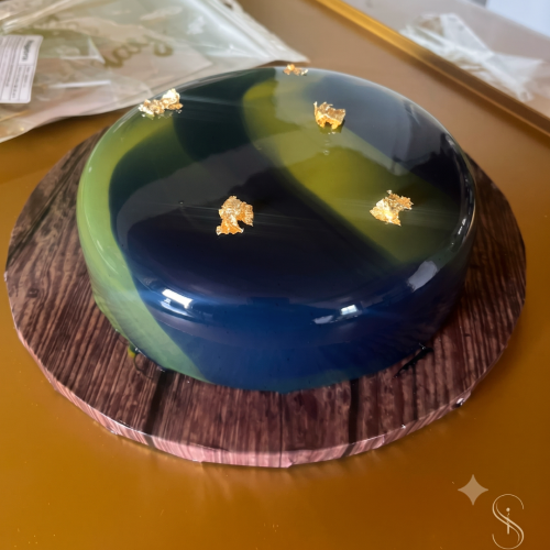 Mango-Maracuja-Mousse-Torte mit glänzender blau-grüner Glasur und goldener Dekoration in Leipzig