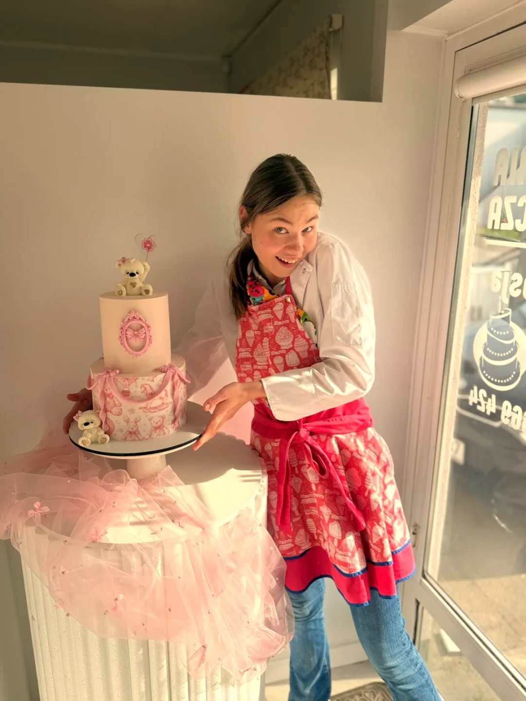 Ein junges Mädel zeigt auf eine 2-Etagen Torte. Schön dekoriert.